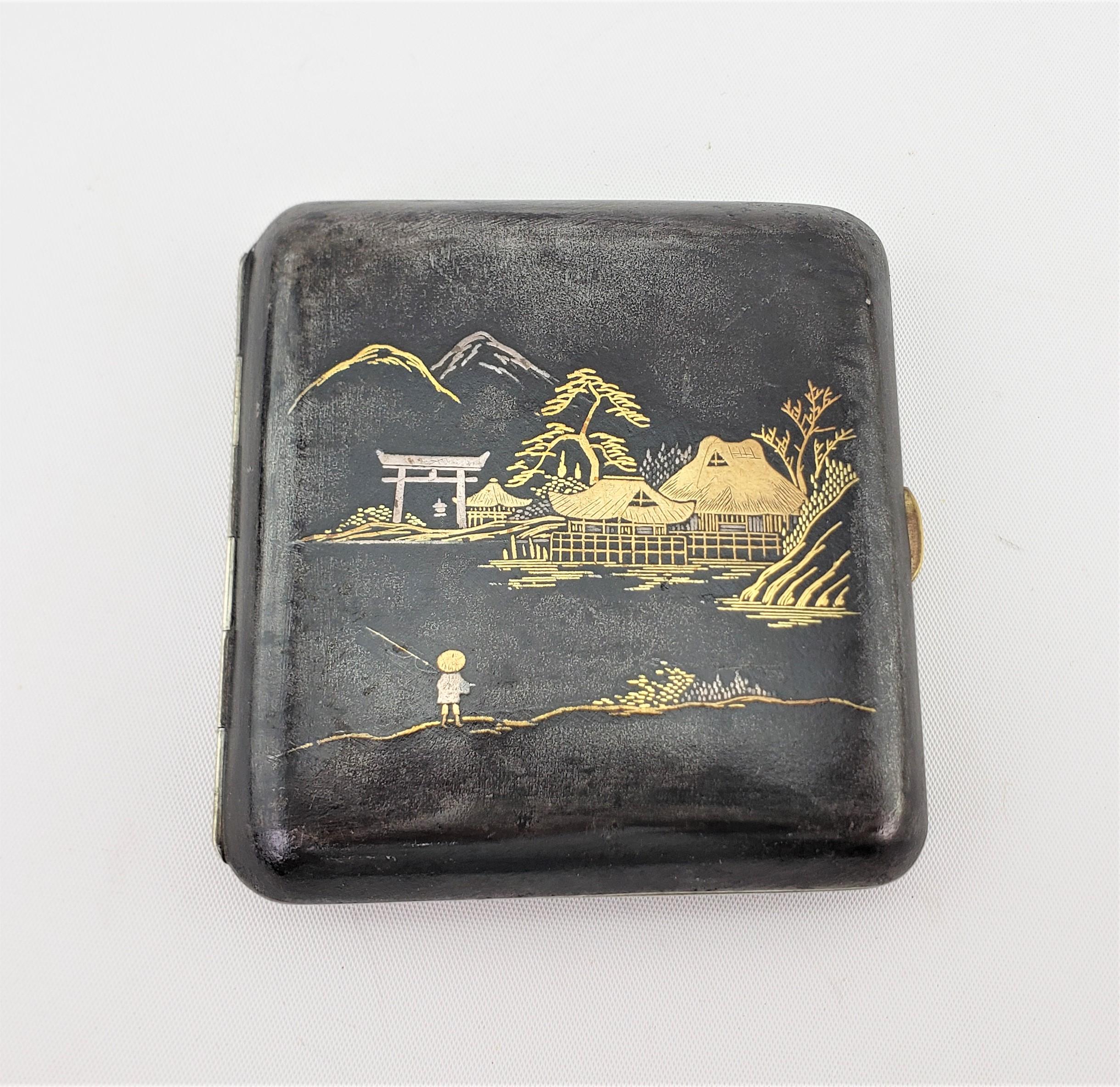 This antique Japanese cigarette case is signed by an unknown artist, and dates to approximately 1920 and done in an Anglo-Japanese style. This damascene styled cigarette case is done with oxidized metal and decorated with a well executed Japanese