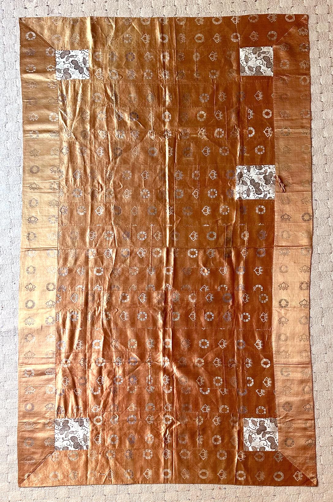 Un Kesa (vêtement de moine) japonais composé de treize colonnes de patchworks d'un fin tissu de soie chatoyant de couleur orange saumoné, dont la teinte change subtilement sous différents angles de lumière. Les broderies fines et délicates de deux