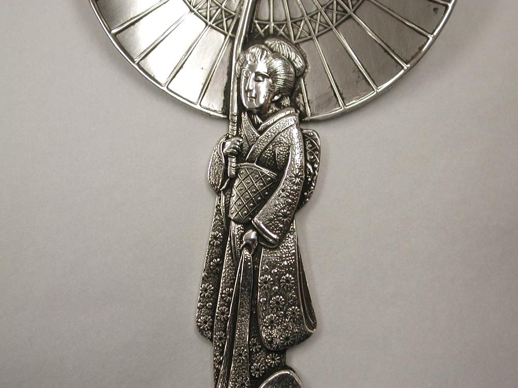 Antique Japanese figural Geisha girl silver tea caddy spoon, circa 1900
This is a beautiful example of Japanese craftsmanship, depicting a geisha girl holding a parasol
which forms the bowl of the spoon.
As most people know, tea is an important