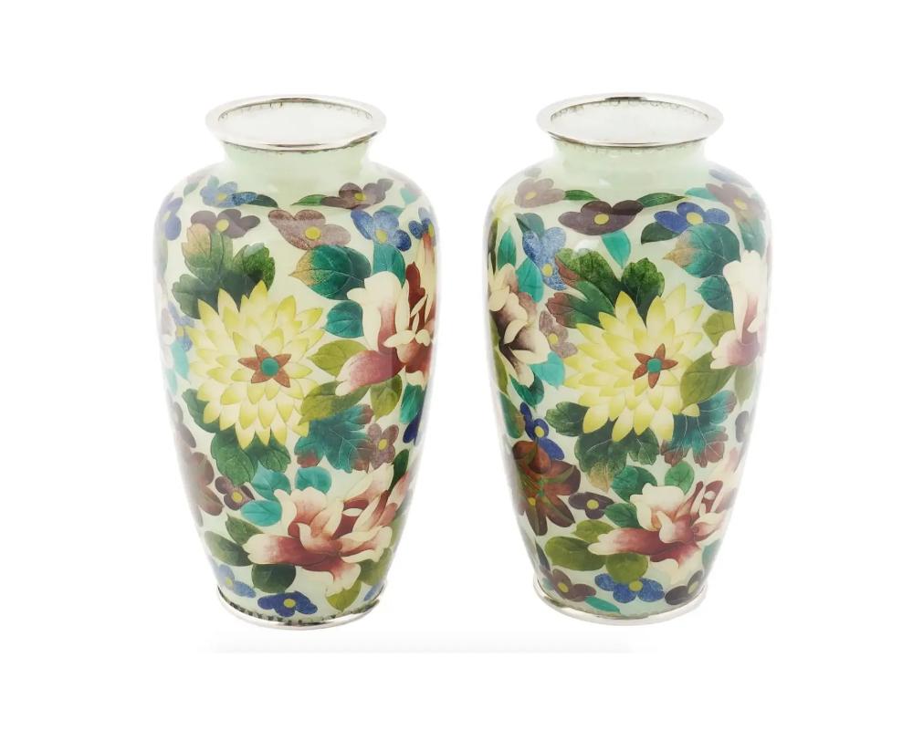 A pair of antique Japanese Meiji era enamel vases. The vases are covered with polychrome enamel foliage and floral patterns made in the Plique a Jour technique. Circa: early 20th century. Unmarked. Plique a jour is a vitreous enamelling technique