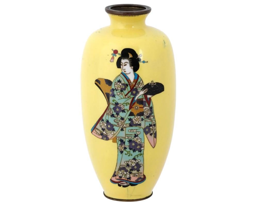 An antique Japanese, late Meiji era, enamel over copper vase. The urn shaped vase is adorned with a polychrome image of a Geisha lady in a traditional costume against a bright yellow background made in the Cloisonne technique. The neck is decorated