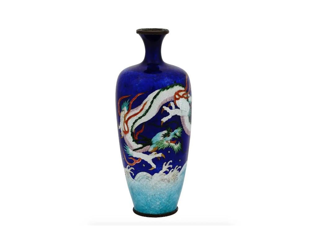 An antique Japanese Meiji period Ginbari enamel vase. The ground of the vase is enameled in blue and cobalt blue shades. The vase is enameled with a polychrome image of a dragon over the waves made in the Cloisonne technique. Ginbari is a Japanese