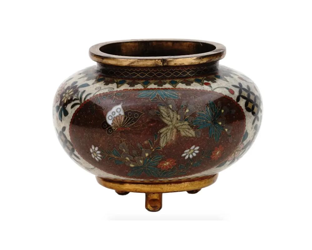 An antique Japanese Meiji Era tripod enamel metal censer koro. Circa: late 19th century. The sphere form ware is enameled with polychrome medallions with blossoming flowers and butterflies surrounded by floral and foliage patterns made in the