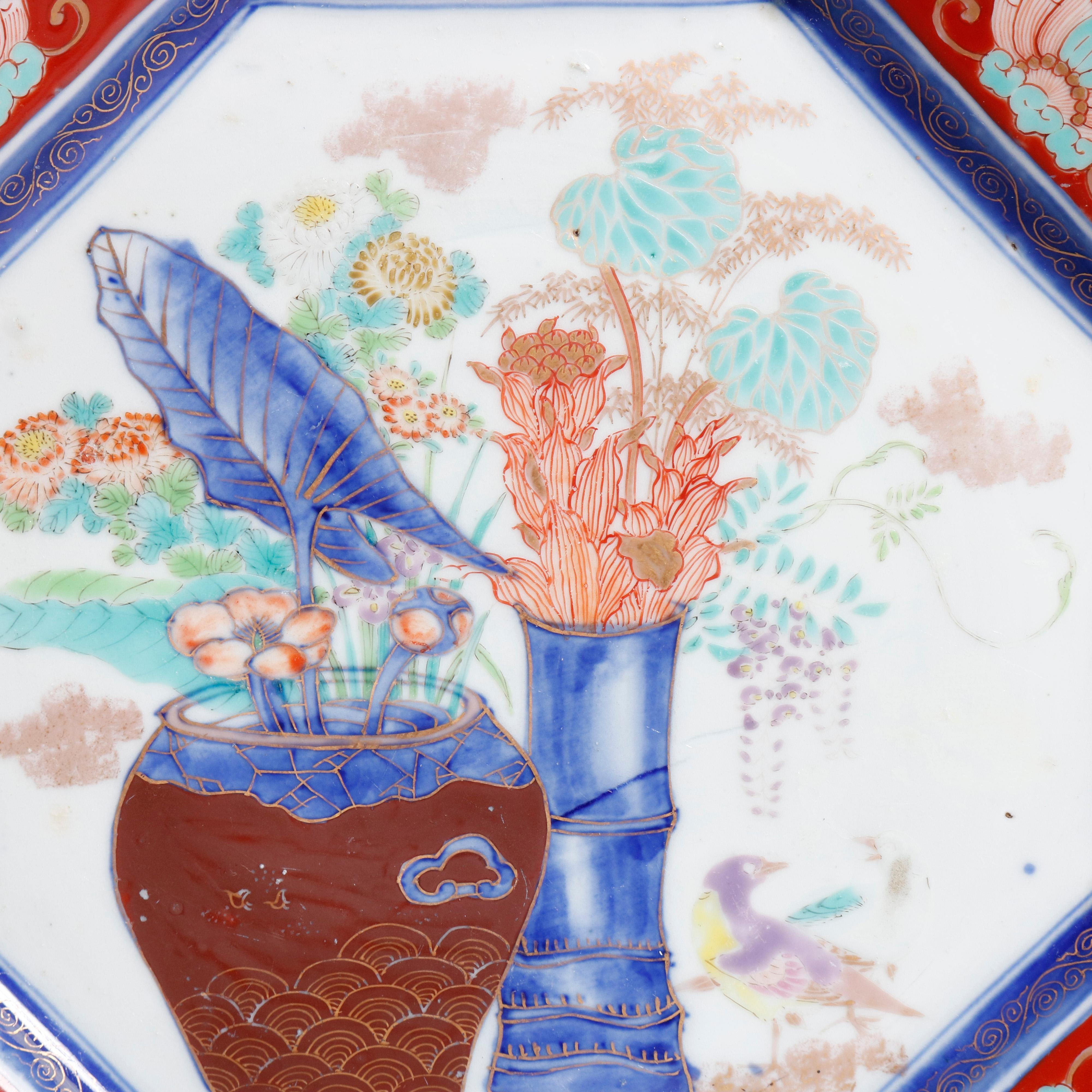 An antique Japanese porcelain charger offers octagonal form with central garden urn scene and faceted border with dragon and foliate reserves, gilt highlights throughout, en verso chop mark signed with blue decoration on rim, circa 1900

***DELIVERY