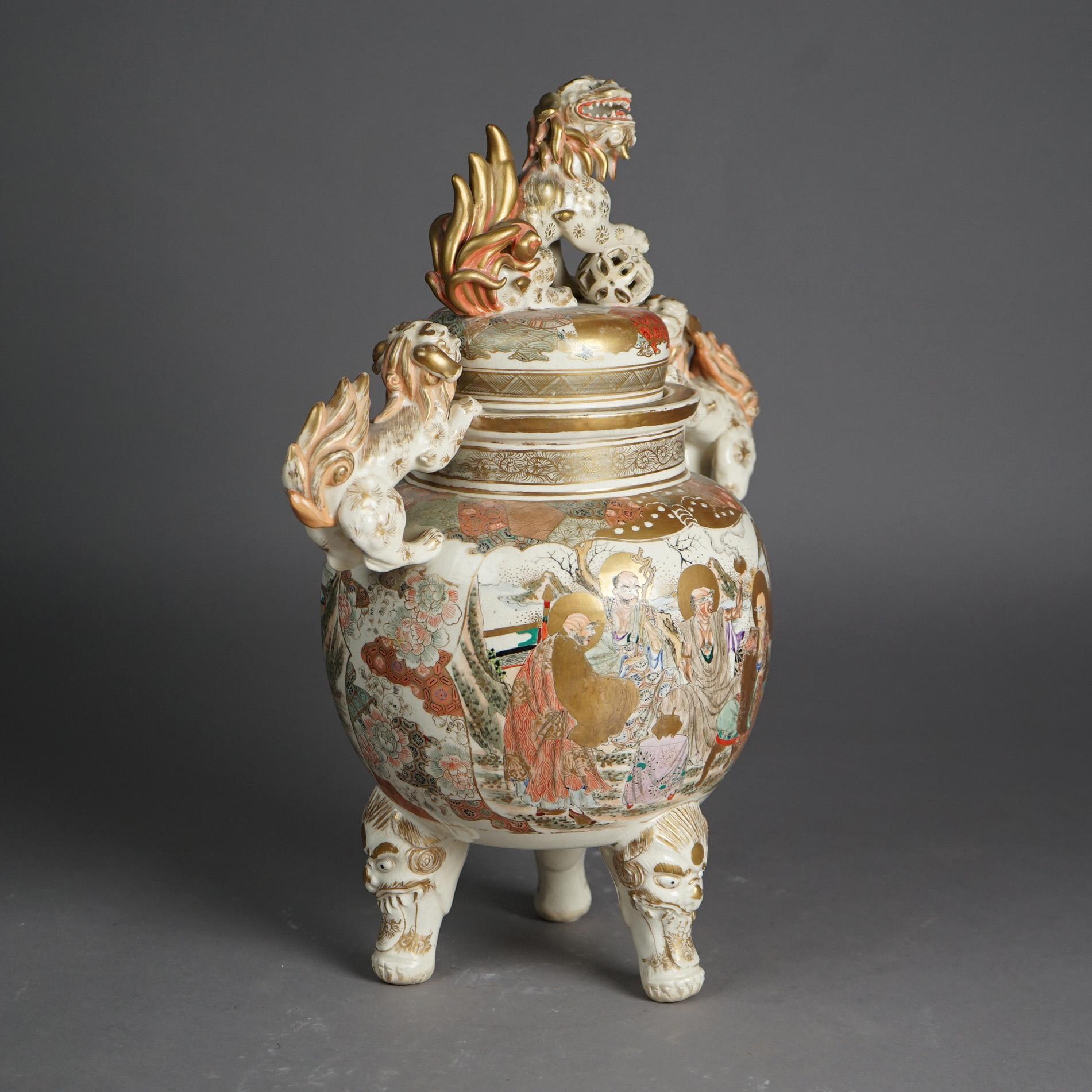 An antique Japanese censer offers porcelain construction in lidded urn form and having foo dog finial and handles; vessel with hand painted figures; raised on three legs; gilt highlights throughout, c1920

Measures - 17.5
