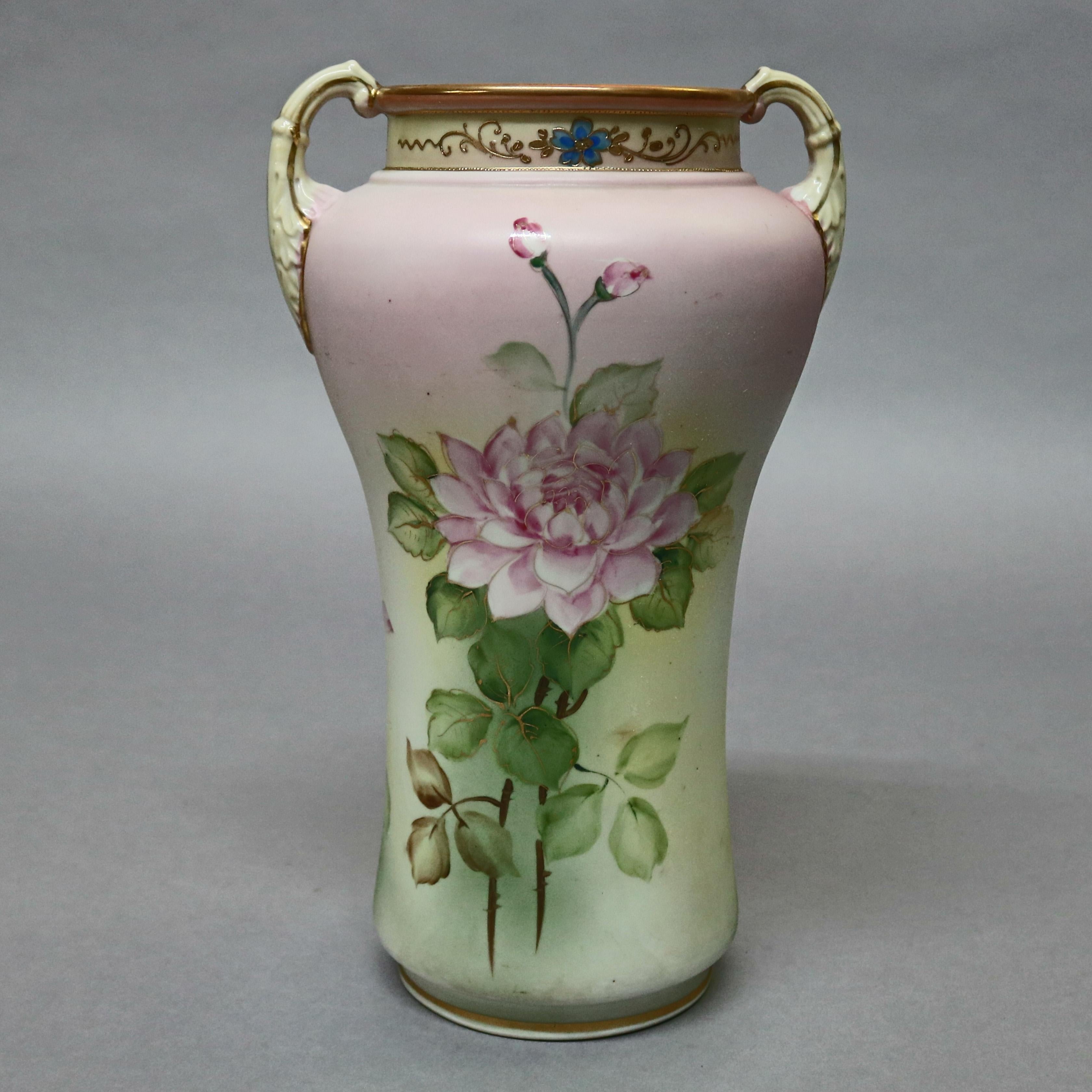 An antique Japanese Nippon porcelain vase offers urn form with gilt double foliate form handles vessel with hand painted floral motif with gold gilt highlights, and neck having blue and gold floral vine, stamped on base as photographed, circa