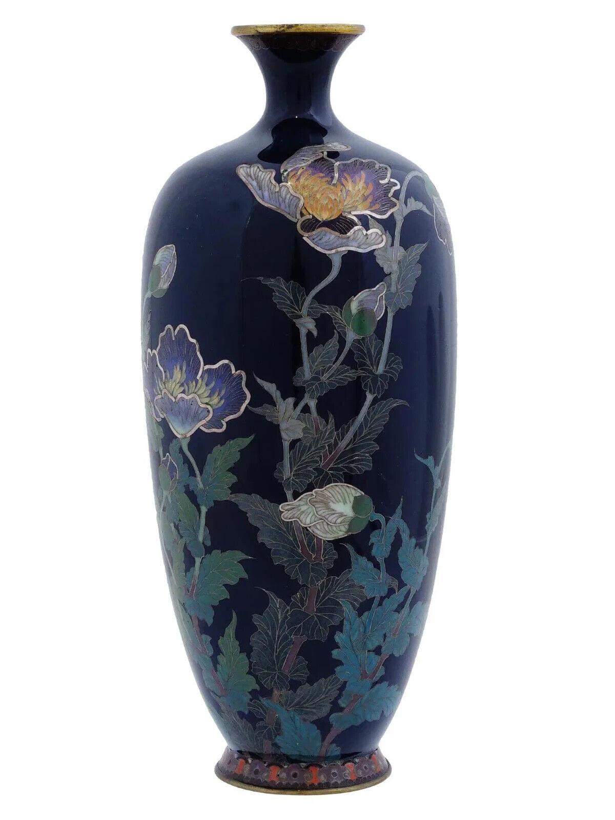 Antiguo jarrón japonés de cobre con diseño de esmalte cloisonné. Finales del periodo Meiji, escuela Hayashi. Tiene forma de balaustre y cuello corto. Color de fondo azul cobalto profundo. El diseño esmaltado representa flores con bordes estampados.