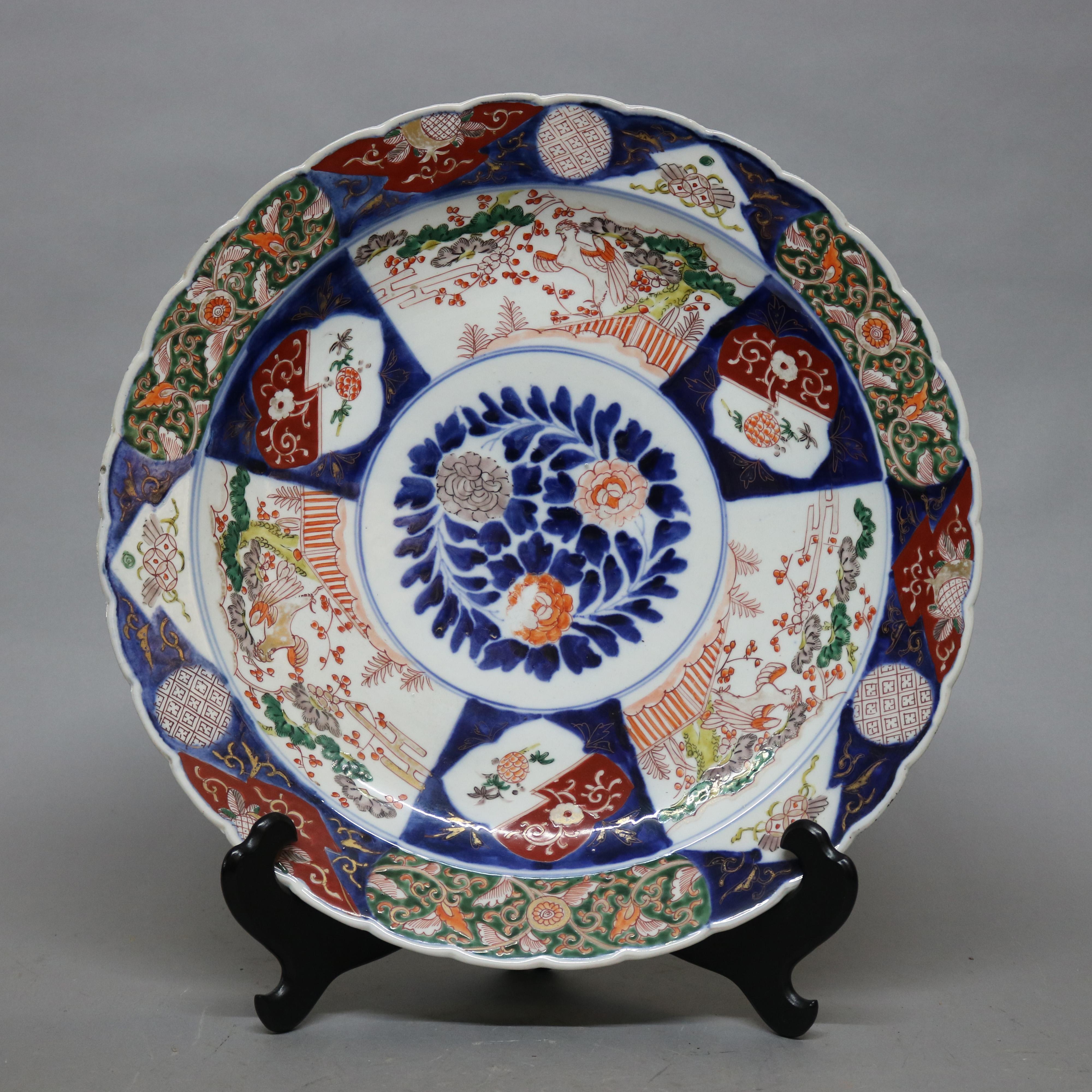 An antique Japanese Imari porcelain charger offers scalloped rim with central floral medallion and paneled borders with garden scenes having birds, gilt highlights throughout, en verso blue decoration, circa 1900

Measures: 2