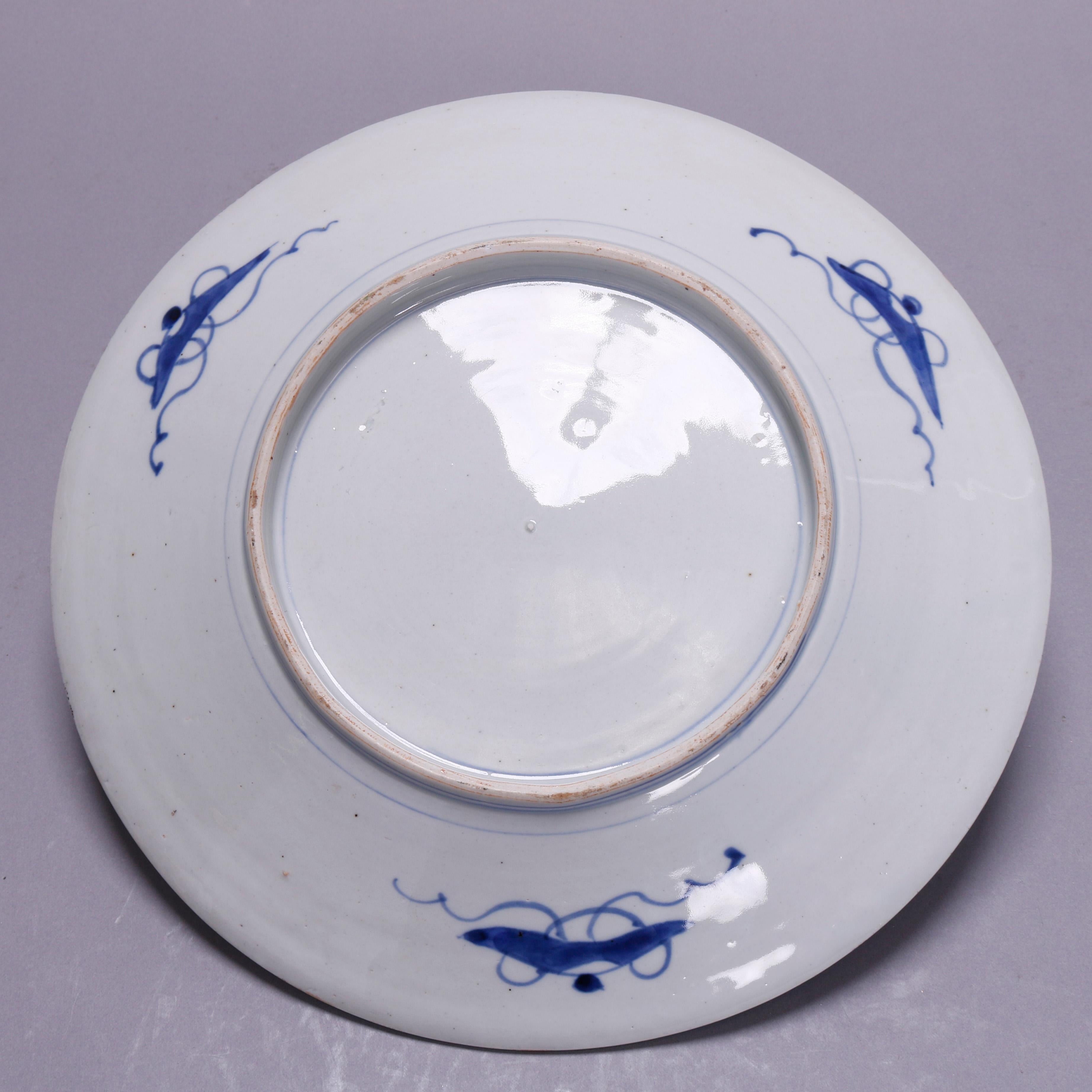 An antique Japanese Imari charger offers porcelain construction with well having hand painted stylized floral decoration with surrounding rim with reserves of garden scenes, en verso blue decorated, circa 1910.

Measures: 2