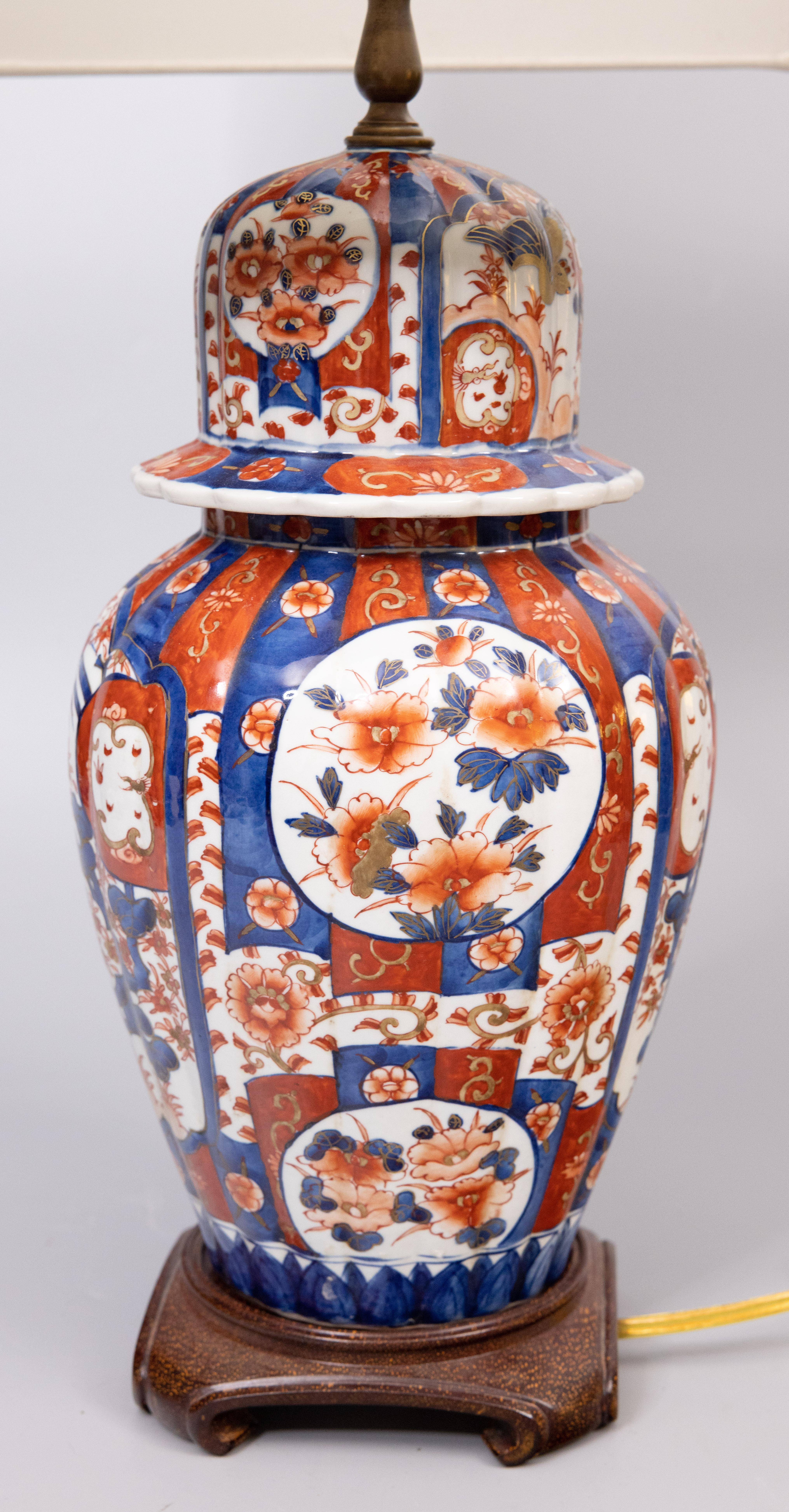 A gorgeous antique Japanese Imari lidded vase or ginger jar lamp mounted on a hardwood base, circa 1900. This fine vase is a nice large size and has a lovely ribbed shape and hand painted birds and floral design in the traditional Imari colors. It