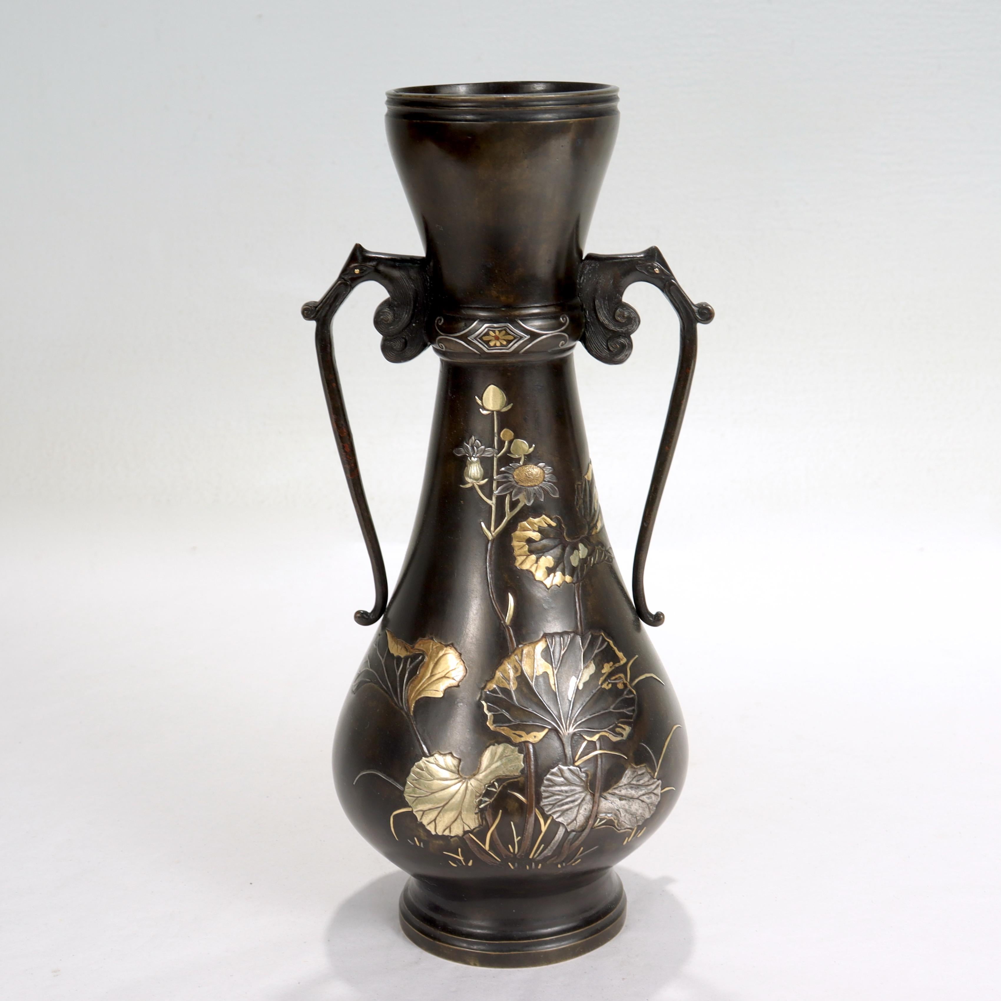 A fine antique Japanese double-handled bronze vase.

With mixed metals (gold, silver, and copper) inlay to the neck, neck handles and raised decoration. (Likely Meiji period), raised depictions of giant butterbur (fuki) to the body and figural