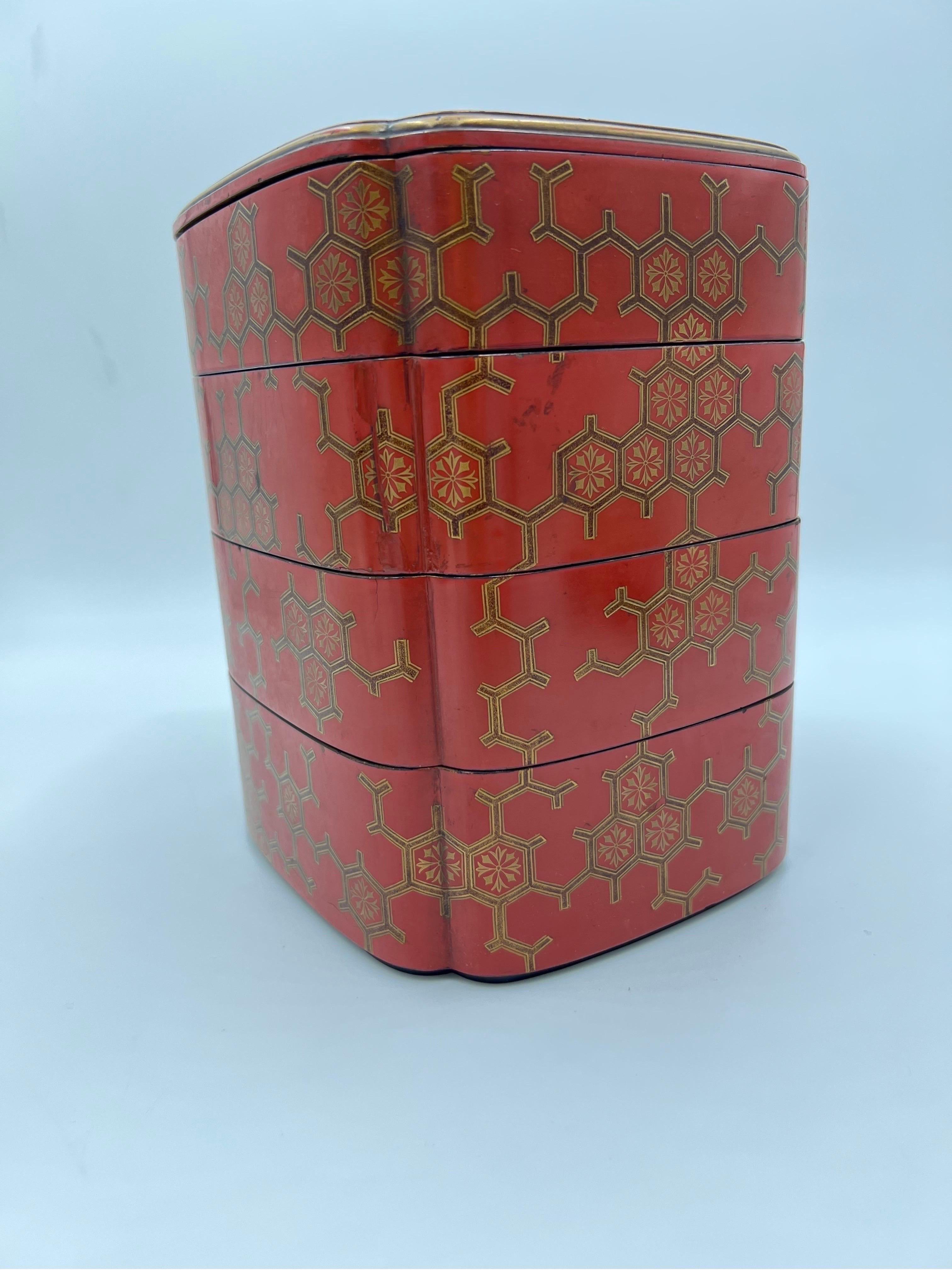 An antique Japanese red lacquerware bento box. Constructed in 5 pieces with 4 compartments, each having a gilt border, chromosomal style decoration to body and scalloped corners. Unmarked.