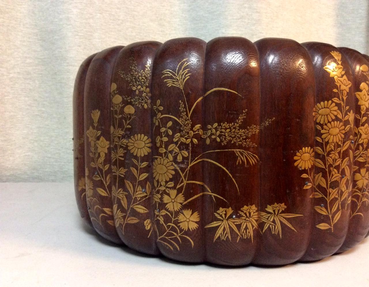 The wonderful hibachi is hand carved with ribs and hand-decorated in low-relief with Makie lacquer and silver dots. It depicts a floral motif of chrysanthemum, lilies and seasonal flower blooms set amongst lush foliage and tall Pampas grass. 
The