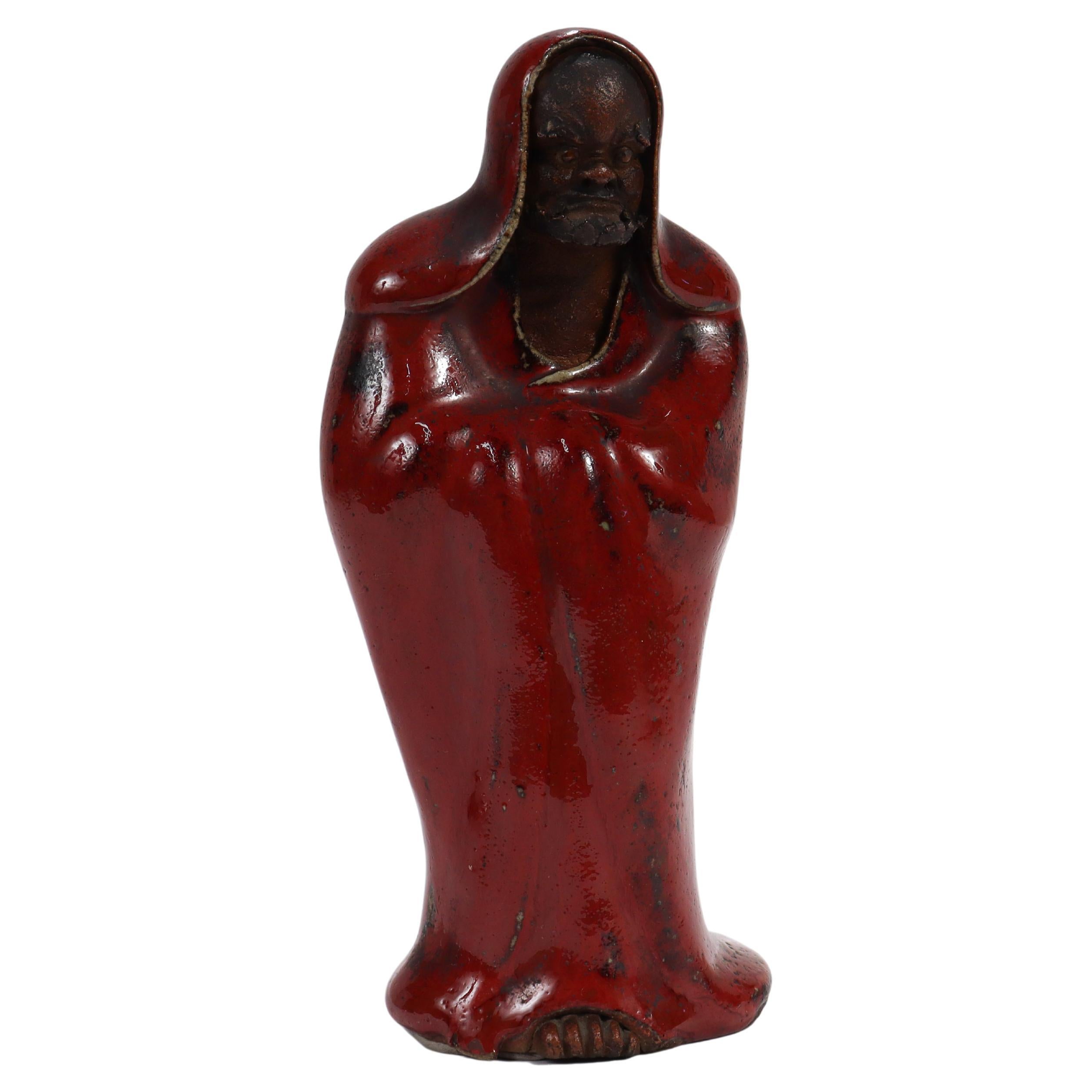 An fine, antique Japanese pottery Daruma figurine.

In the form of a Daruma, a depiction of Bodhidharma the semi-legendary founder of Zen/Chan Buddhism.

The figure's face and protruding toes are an unglazed dark brown and his robe has a dark red