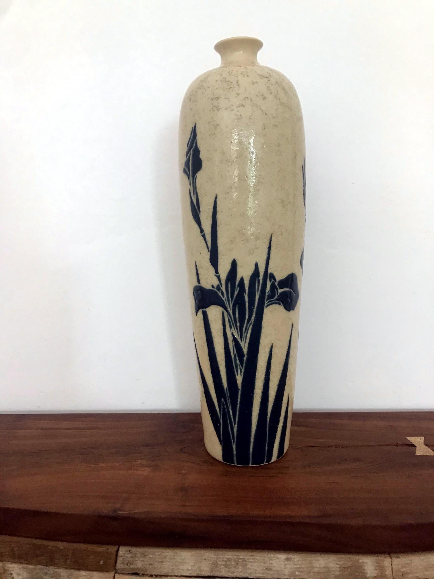 An elegant vase made in Kyoto, Japan, circa 1920s. With a graceful elongated Mei-Ping form, it was likely used as a flower holder during the tea ceremony. The stoneware body has an incised and raised design of Irises in an over glazed indigo blue,