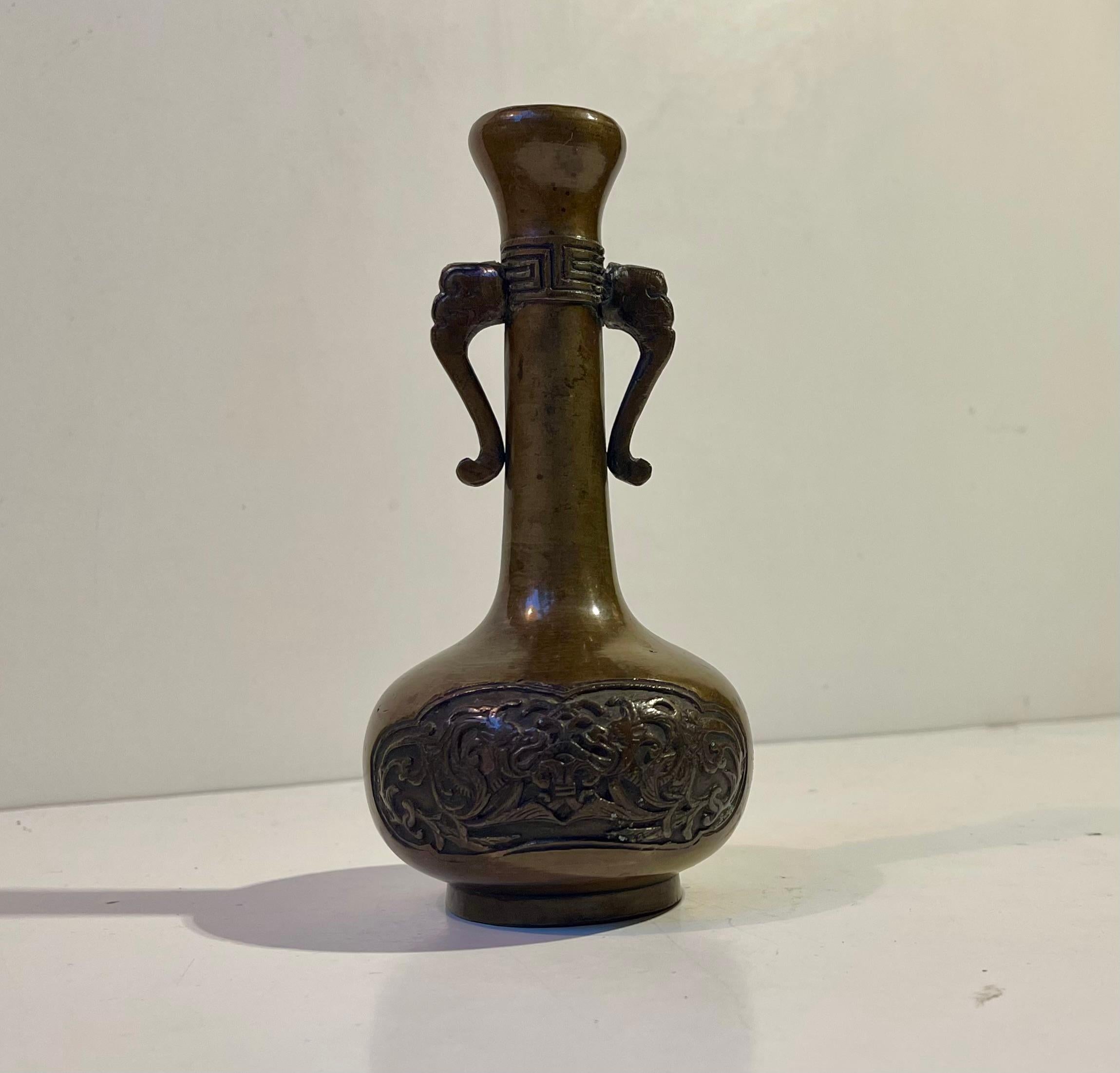 Vase à bourgeons de la fin du XIXe ou du début du XXe siècle de la période Meiji, coulé en bronze, avec un relief de dragon en bronze gravé et des poignées d'éléphants stylisés. Il s'agit d'une pièce d'exportation qui est probablement arrivée en