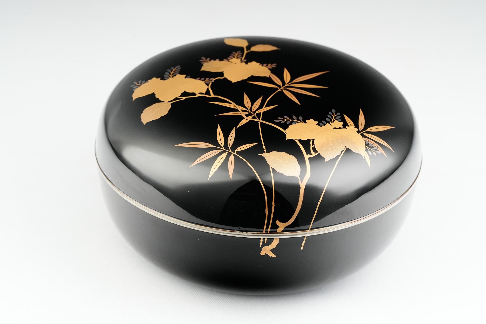 Ce plat à bonbons kashiki ancien présente un motif raffiné de paulownia et de bambou exécuté en maki-e d'or fin sur un fond de laque noire profonde. Le paulownia est associé à la pureté et à la bonne fortune, tandis que le bambou représente la force