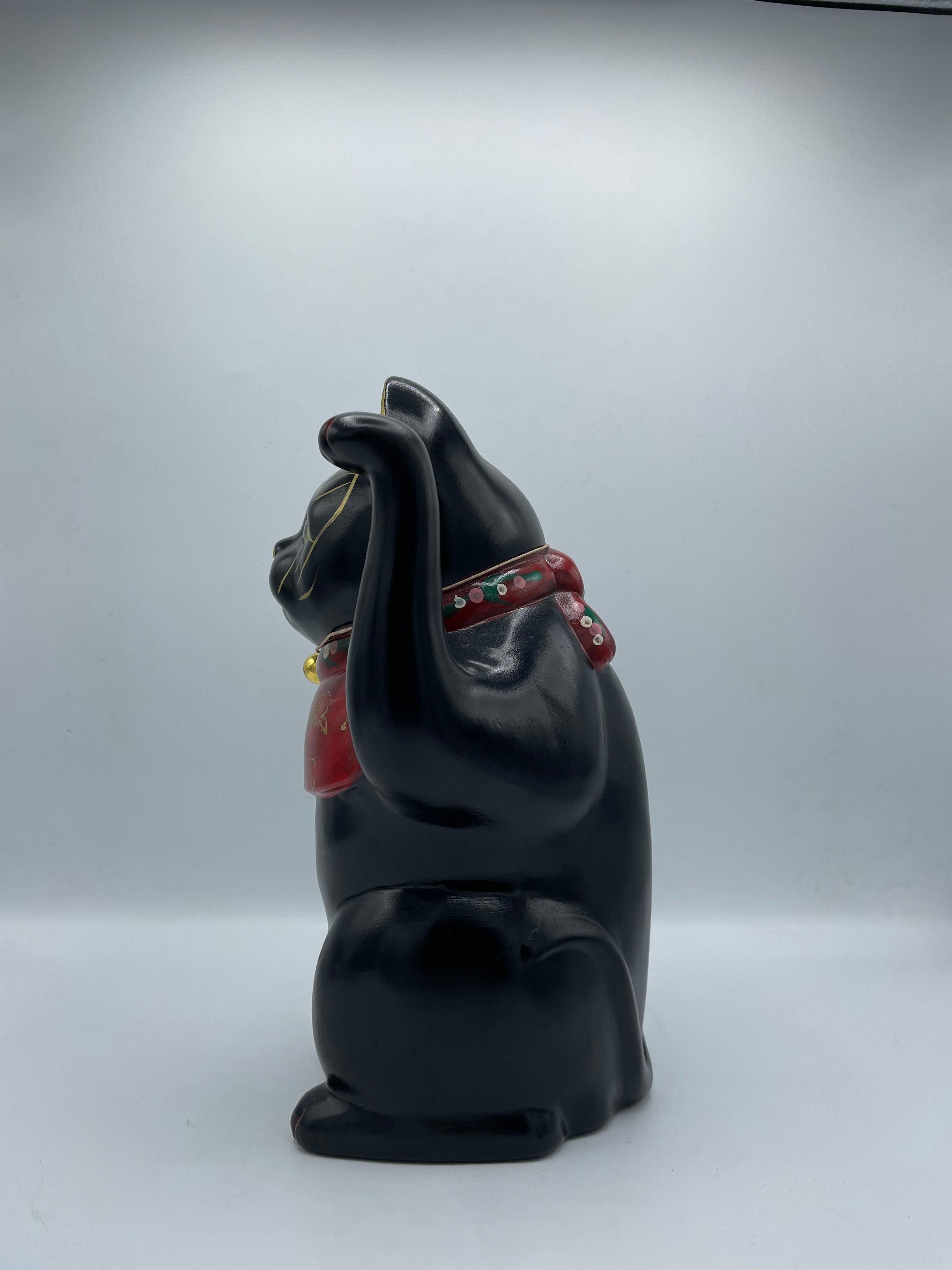 This is an antique maneki neko cat object. It is painted in black and around the neck, it is in red.
This object was made in Japan around 1960s in showa era.

Dimensions: 13.5 x 13 x H26 cm

The maneki-neko is a common Japanese figurine which