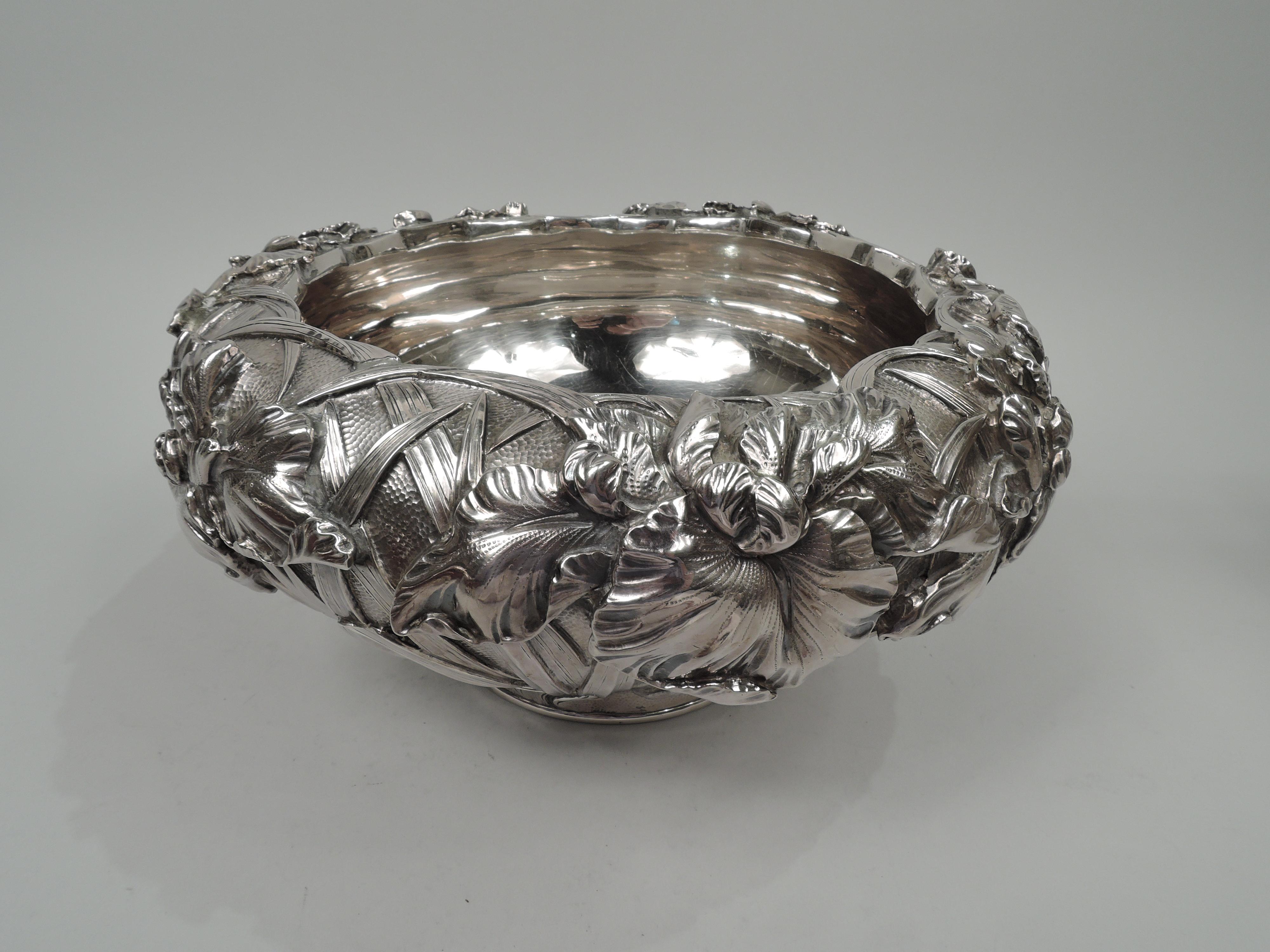 Turn-of-the-century Japanese silver bowl. Tapering sides on short inset foot. Sides have high-relief iris flowers with loose and splayed tendrils, and swaying tendrils and stems in eddying water. Fluid and tactile period motif on spot hammered
