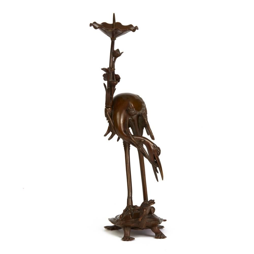 A very fine quality antique Japanese Meiji bronze pricket stick modelled as a crane standing on the back of a turtle holding a lotus bud in its mouth. The pricket stick has a wonderful age patina with a detachable sconce modelled as a raised Lotus