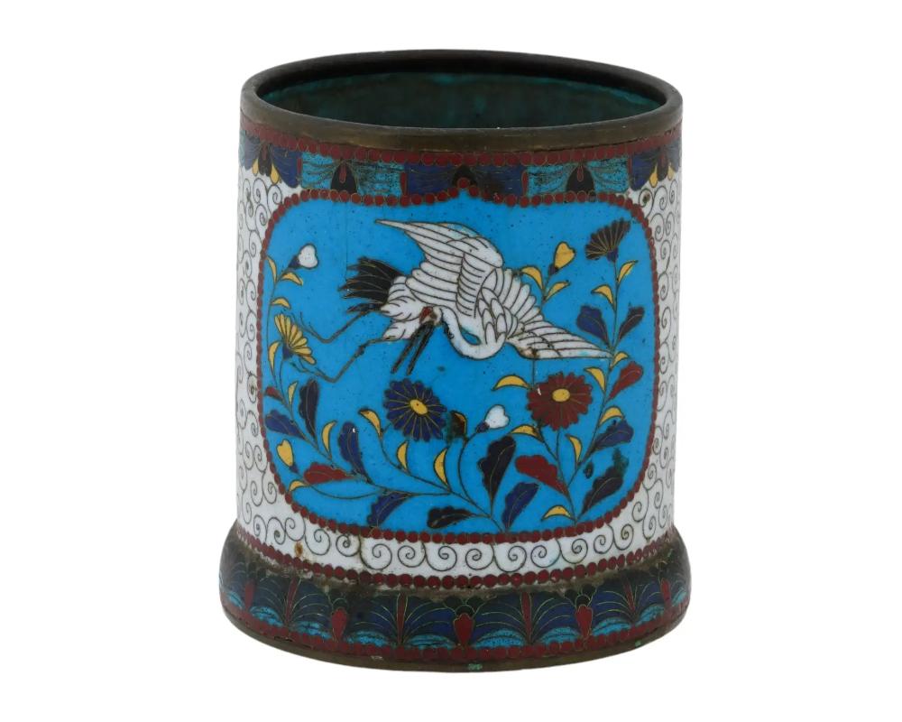 An antique Japanese Meiji Era cylindrical shaped enamel brush pot. Circa: 19th century. The cylindrical form pot is enameled with polychrome medallions with cranes in blossoming flowers surrounded by a swirl motif made in the Cloisonne technique.