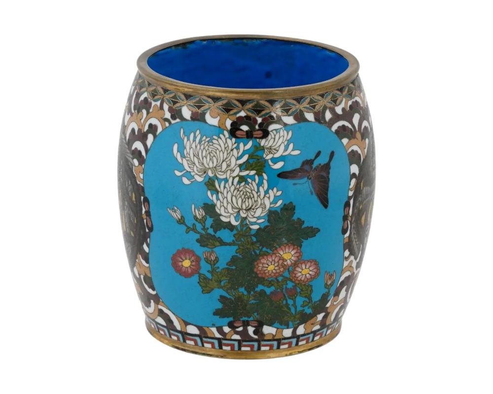 An antique Japanese Meiji Era cylindrical shaped enamel over brass brush pot. Circa: 19th century. The cylindrical form pot is enameled with polychrome medallions with butterflies in blossoming flowers surrounded by a scrollwork motif and images of