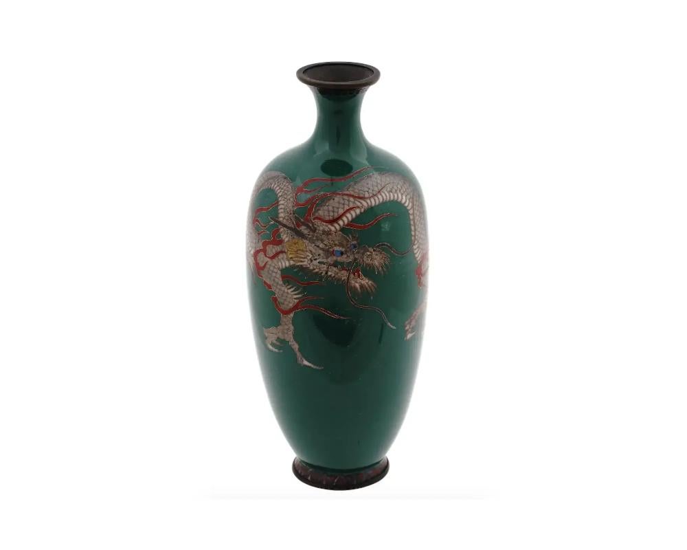 An antique Japanese late Meiji era enamel metal vase.

The amphora shaped vase with a narrow fluted neck. The vase is adorned with a polychrome image of a dragon made in the Cloisonne technique on a dark green ground.

The base is adorned with a