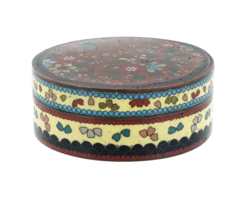 An antique Japanese copper Kogo box for incense. Early Meiji period, ca. 1870s. Round shape. Polychrome cloisonne enamel design, flowers and butterflies ornament in red and yellow color palette. The interior is in turquoise blue color. Collectible
