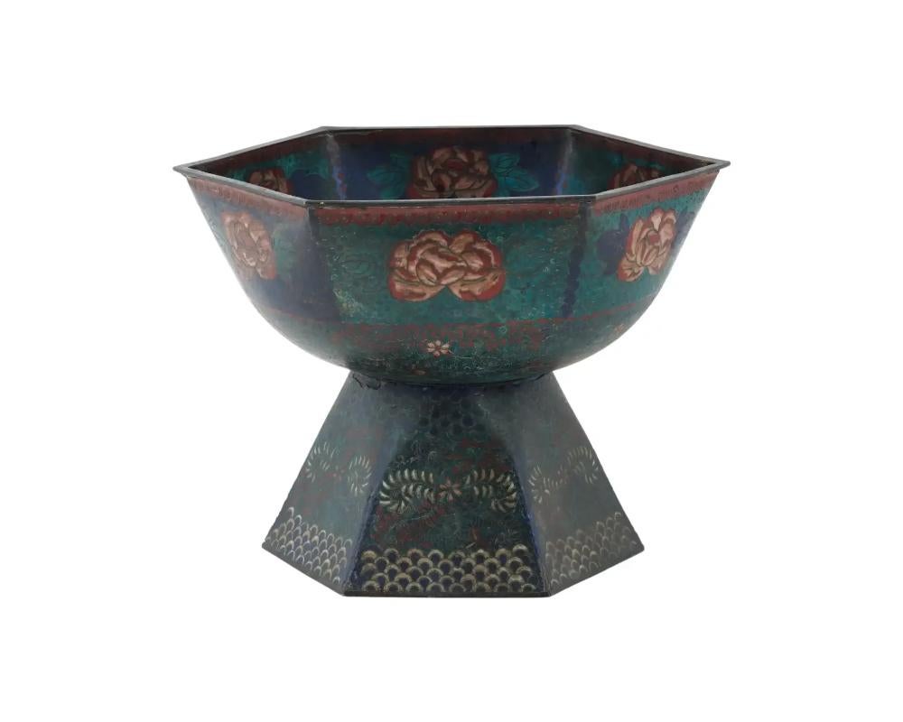 An antique footed Japanese, Meiji era, enamel over copper tazza bowl. The exterior of the ware is covered with polychrome enamel panels with blossoming flowers surrounded by floral, foliage, foliate scroll, and swirl ornaments made in the Cloisonne