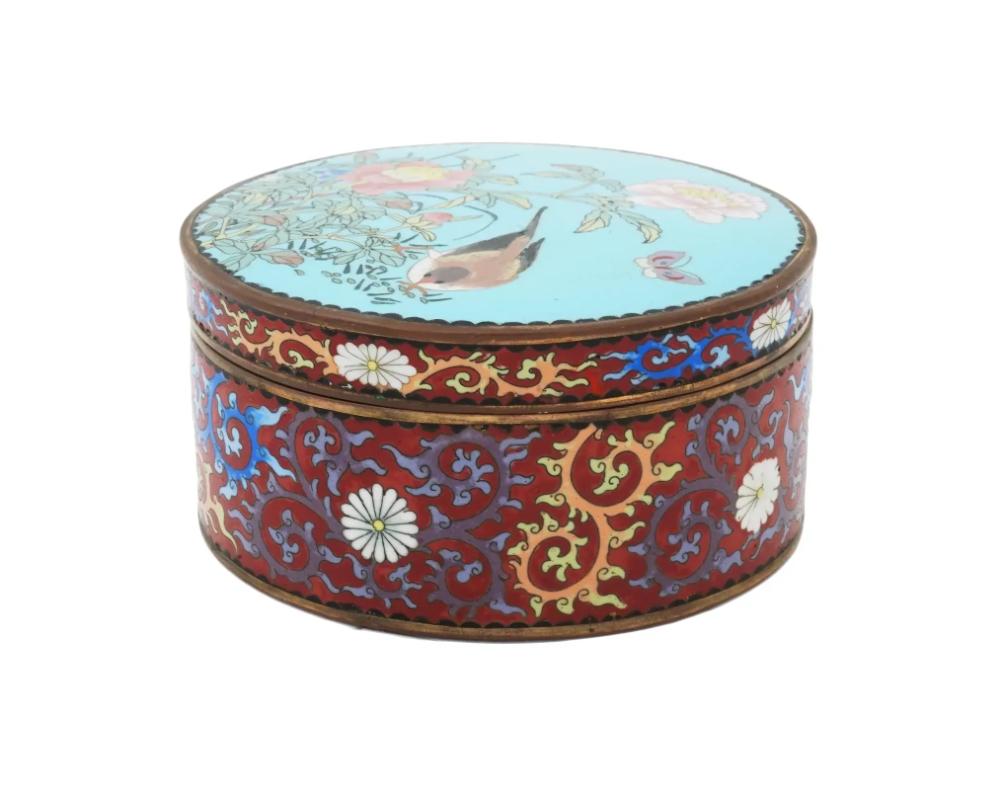An antique Japanese, late Meiji era, covered enamel over brass jewelry or trinket box. The body of the ware is enameled with floral and foliage motifs made in the Cloisonne technique. The cover features a polychrome enamel design depicting a bird