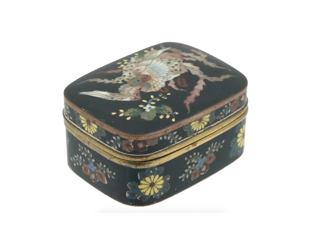 An antique Japanese Meiji Era covered enamel brass kogo or box for incense. Circa: late 19th century to early 20th century. The box is enameled with polychrome floral and foliage patterns and an image of a Phoenix bird on the top of the lid made in