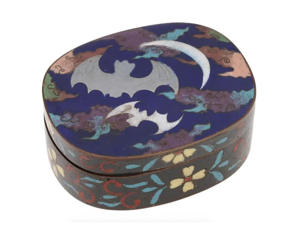 An antique Japanese Meiji Era enamel over brass kogo or box for incense. Circa: late 19th century to early 20th century. The lid of the ware is enameled with polychrome images of bats, and a half moon surrounded by a cloud motif made in the