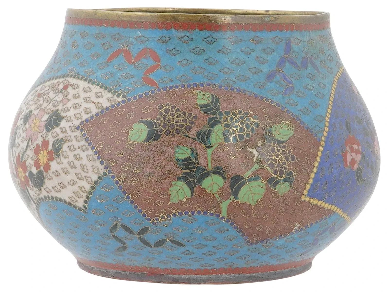 An antique Japanese Meiji era cloisonne enamel brass bowl featuring a bulbous body showcasing detailed floral and foliate motifs, including pink and red blossoms, against a turquoise blue background. Circa: the late 19th to the early 20th century.