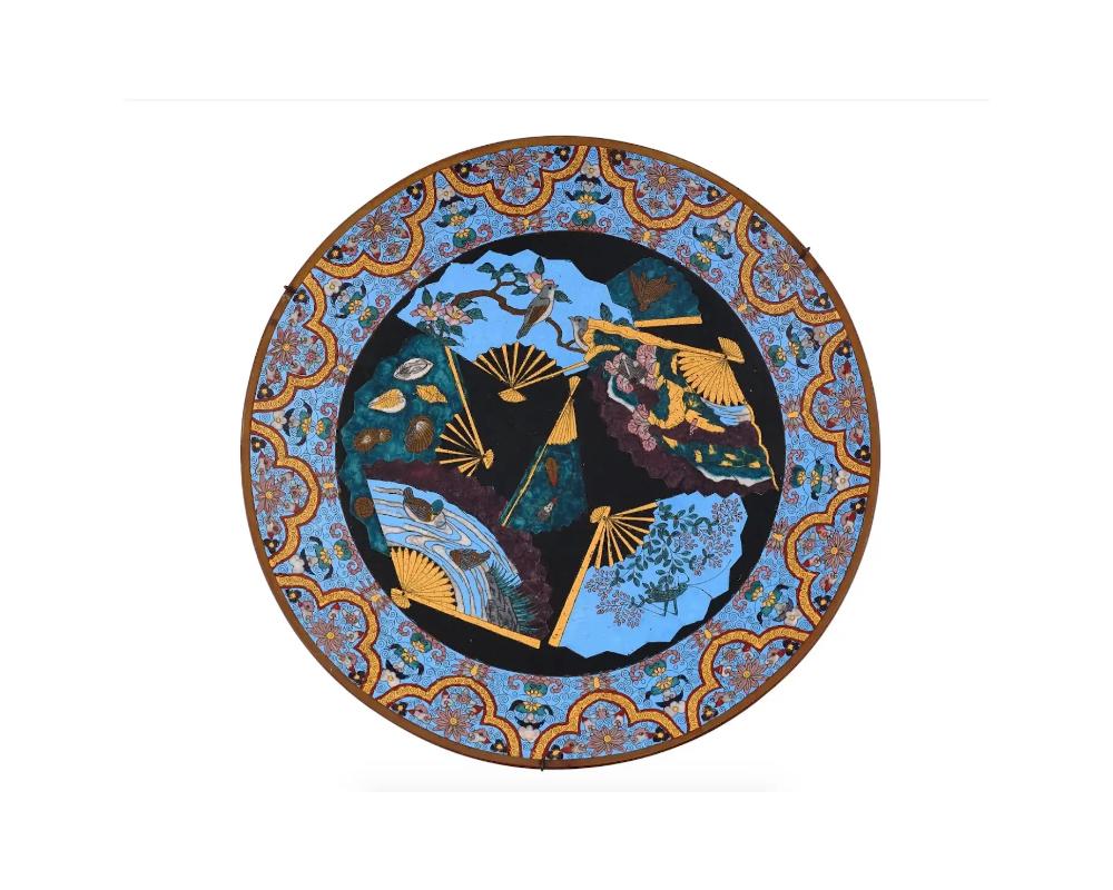A highly decorative antique Japanese Meiji Era enamel plate,

. The interior of the plate is enameled with a polychrome design with images of fans to the center. Each fan is adorned with intricate designs depicting landscapes, birds, insects and