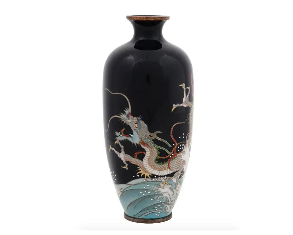 An antique Japanese Meiji period enamel vase. The vase has an amphora shaped body and a narrow neck. The vase is enameled with a polychrome image of a dragon over the waves made in the Cloisonne technique on black ground. Unmarked. Circa: late 19th