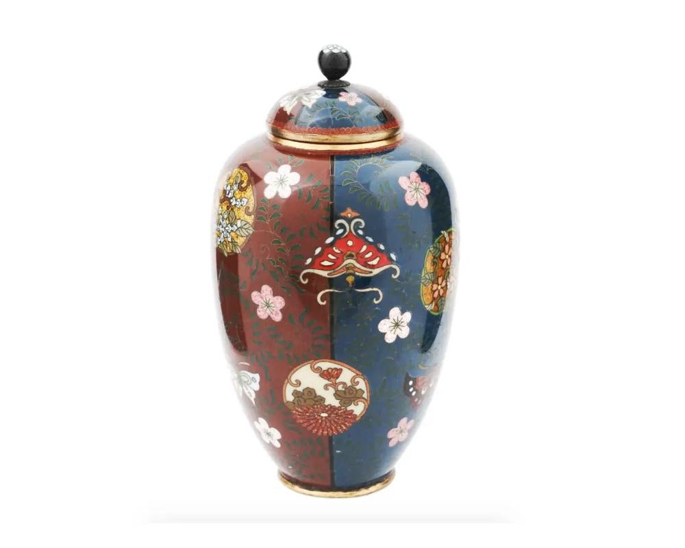 Antico vaso ad anfora giapponese dell'epoca Meiji, a forma di smalto e ottone. L'esterno del vaso è ornato da un disegno continuo smaltato in policromia di tondi floreali stilizzati sovrapposti, tralci di vite e farfalle sparse su pannelli verticali