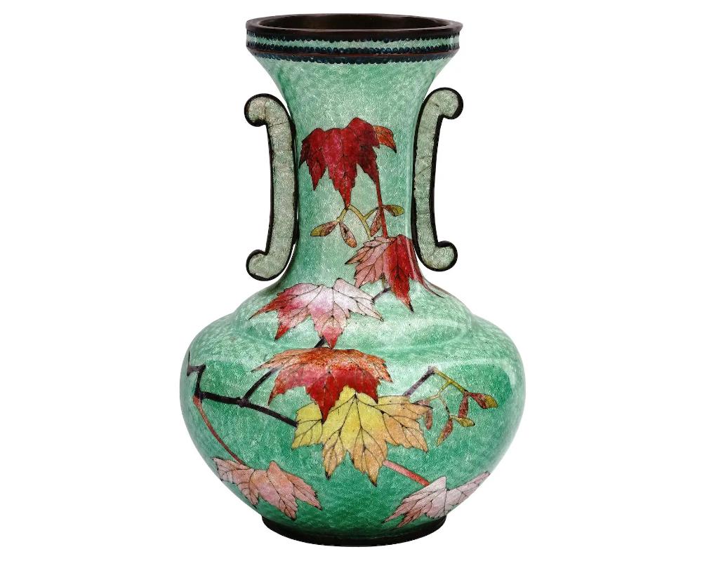 An antique Japanese copper vase with polychrome ginbari cloisonne enamel decor. Late Meiji period,
Squat round shape, long neck and decorative side handles. Green body with red and yellow maple leaf motif.

Ginbari is a Japanese cloisonne technique