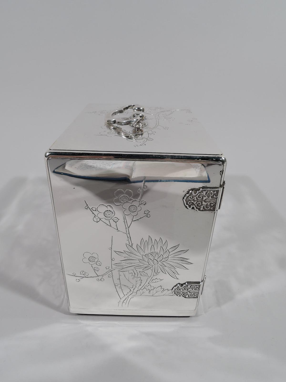 Japanese silver jewelry box, circa 1910. Straight sides and loose-mounted trefoil handle with studded mounts. Sides and top have engraved chrysanthemums, bamboo and blossoming prunus branches. Front has 2 hinged doors with ornamental strap hinges