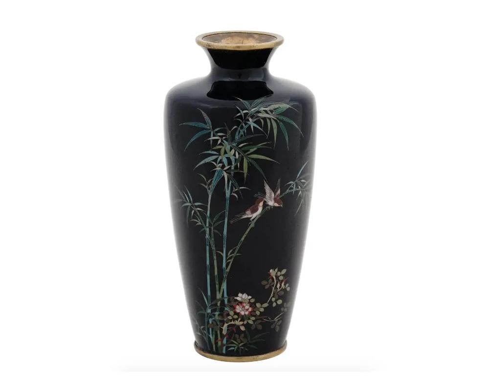 An antique Japanese, late Meiji period, silver wire enamel vase. The vase has an amphora shaped body and a fluted neck. The ware is enameled with a polychrome image of a pair of sparrow birds in bamboo trees and blossoming flowers on the black