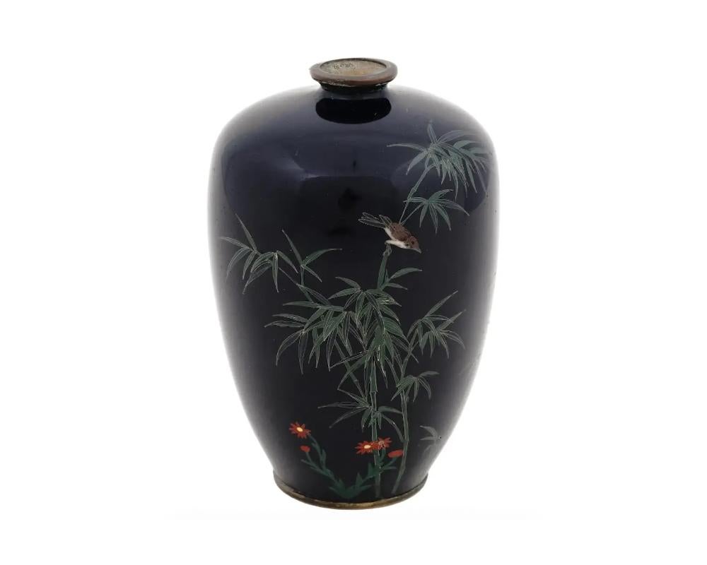 An antique Japanese, late Meiji period, silver wire enamel vase. The vase has an amphora shaped body and a fluted neck. The ware is enameled with a polychrome image of a sparrow bird in bamboo trees and blossoming flowers on the black ground made in
