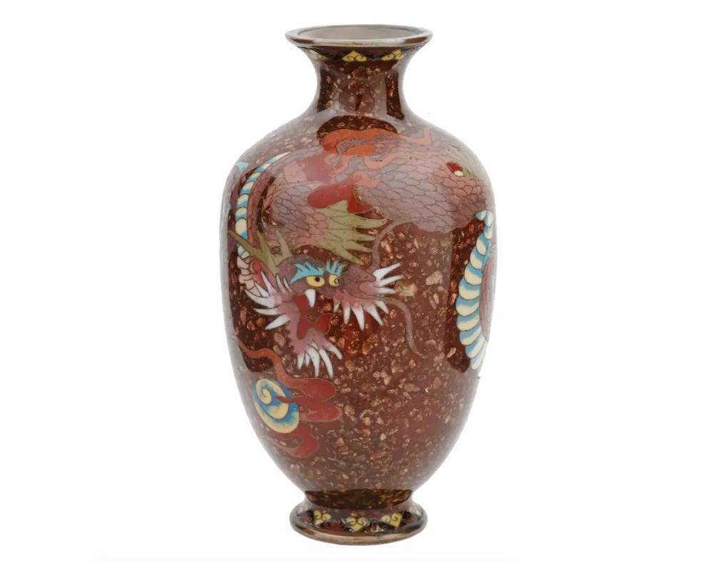 An antique Japanese, late Meiji Era, enamel over brass vase. Circa: early 20th century. The amphora shaped vase is enameled with a polychrome image of a dragon made in the Cloisonne technique on brown ground. The base and the neck of the ware are