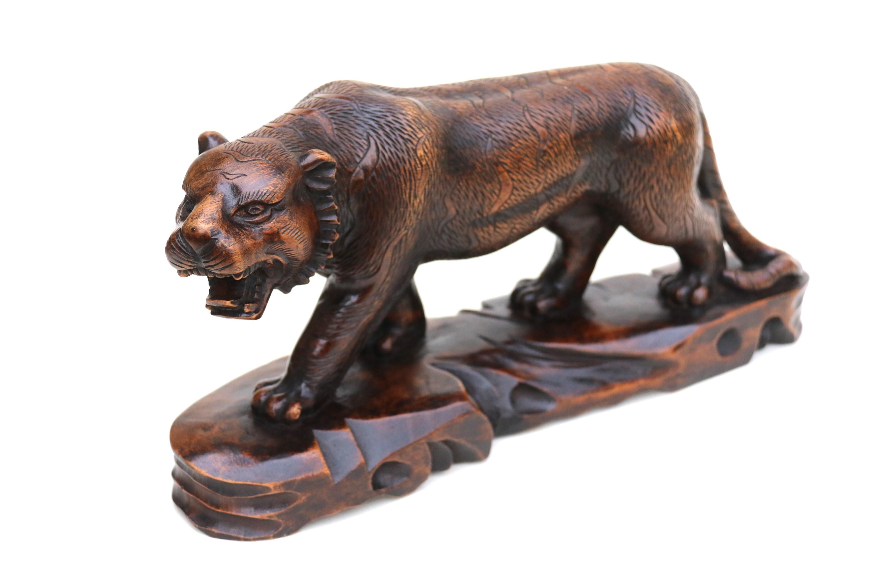 This most pleasing hand carved hardwood Japanese Meiji period okimono depicts a muscular prowling tiger. Its body is slightly lowered in a stalking position with its mouth open showing a formidable array of teeth which in addition to its large paws
