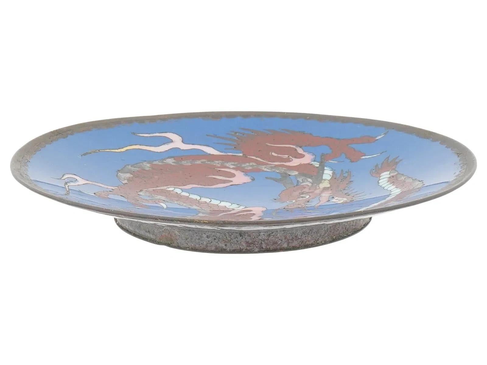 Un antico piatto giapponese in bronzo cloisonne del periodo Meiji, decorato con smalto che raffigura un drago su sfondo blu. L'eleganza della forma e la minuziosa lavorazione a smalto esemplificano la maestria della metallurgia giapponese della fine