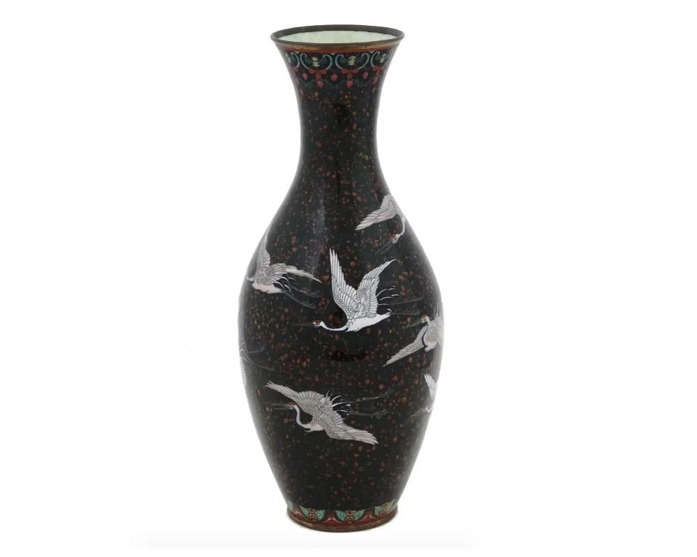 An antique Japanese Meiji period cloisonne vase showcasing the body adorned with intricate cloisonne enamel work, displaying crane designs set against a goldstone background. The long neck of the vase adds to its graceful and elegant appearance.