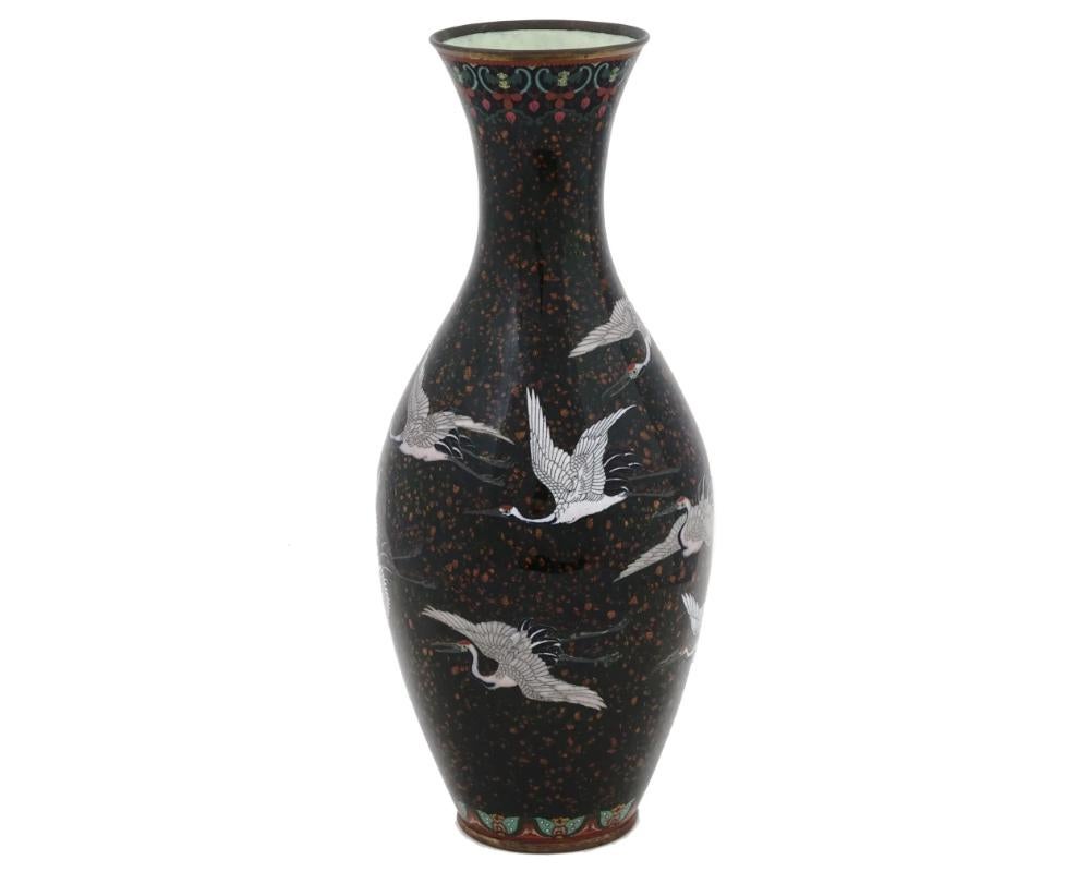 Eine antike japanische Cloisonné-Vase aus der Meiji-Periode, deren Korpus mit komplizierten Cloisonné-Emaillearbeiten verziert ist und Kranichmotive vor einem Hintergrund aus Goldstein zeigt. Der lange Hals der Vase verleiht ihr ein anmutiges und