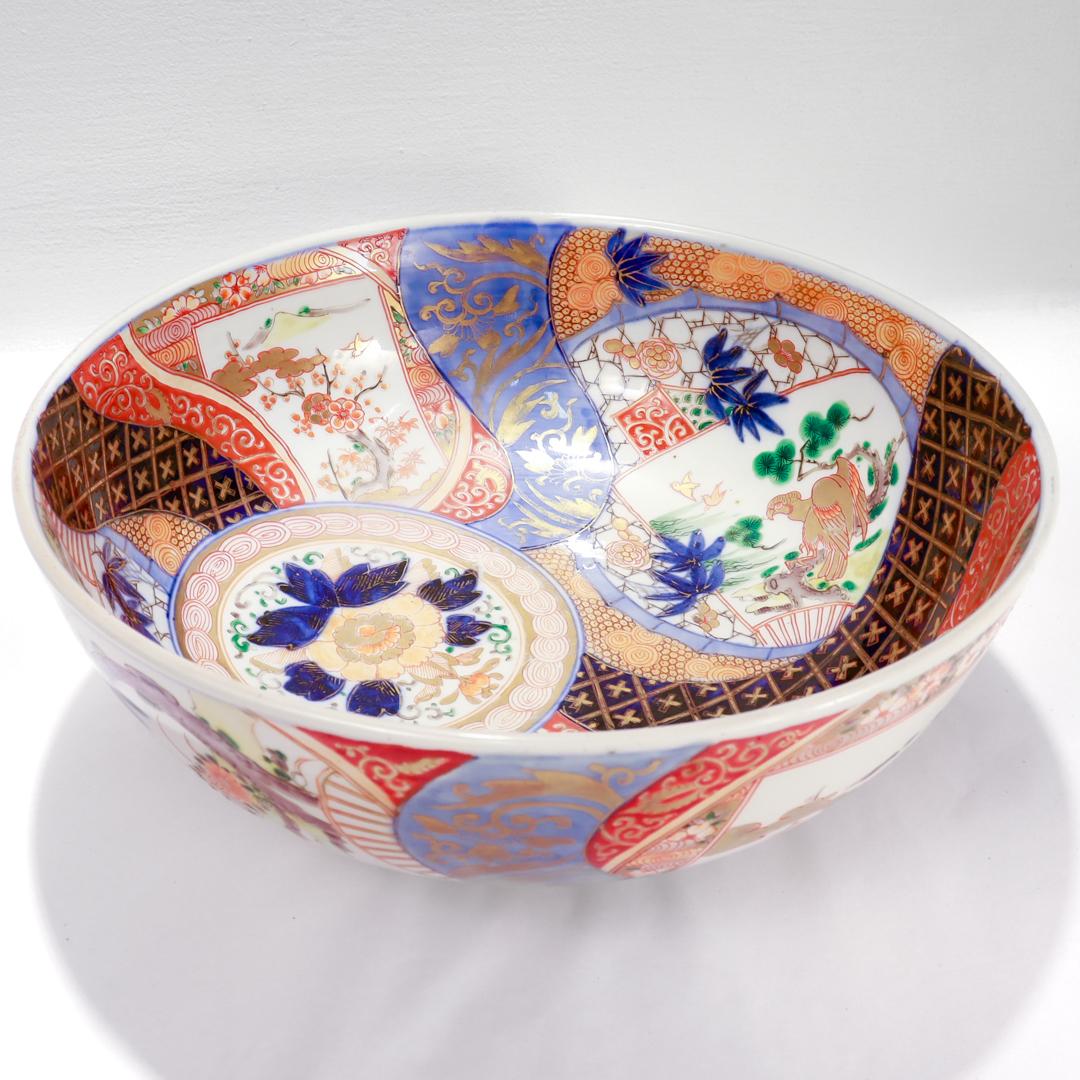 A fine large antique Japanese Meiji porcelain bowl.

With a white ground and extensively gilt throughout. 

Primarily decorated in red, blue, and gold with bits of green, brown, and yellow as accent colors. 

There is a circular flower motif offset