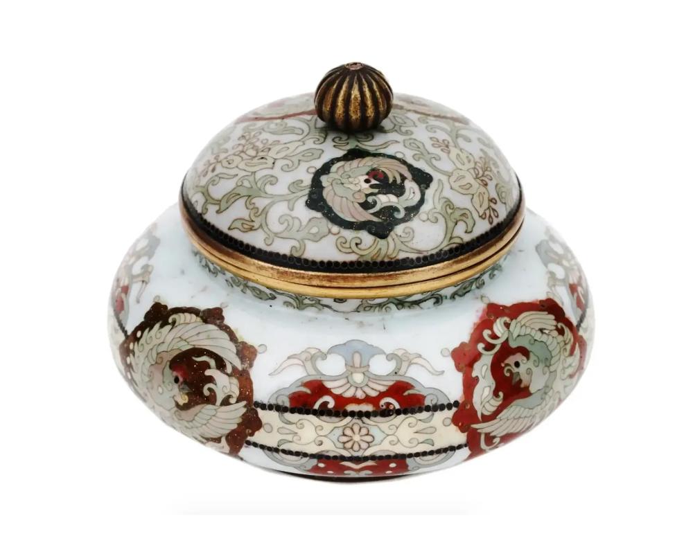 An antique Japanese Meiji period round cloisonne covered jar showcasing the exquisite artistry and craftsmanship of the era. This jar is adorned with intricate cloisonné enamelwork featuring delicate designs. The round shape adds elegance and