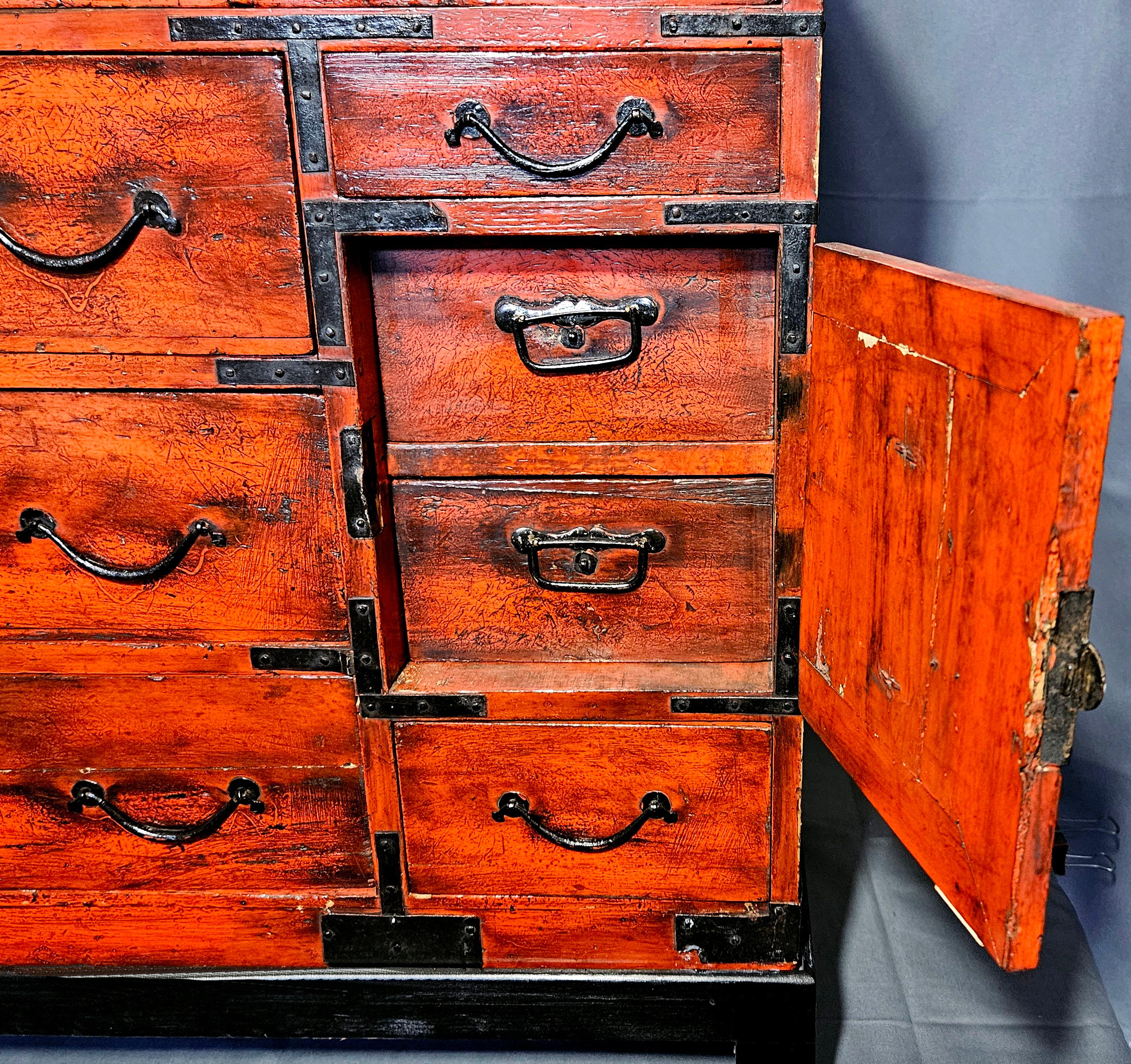Diminutive Meiji Period Storage Cabinet, early 20th c., having a red painted surface and black painted hardware and corner mounts, with side handles, six drawers and one cabinet door concealing two additional drawers, set on a black bracket form