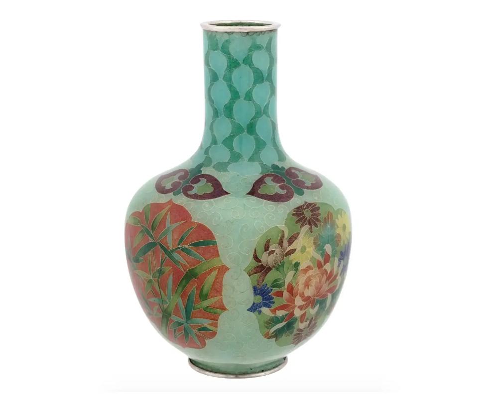 An antique Japanese Meiji period vase of globular form with a straight neck, decorated with silver wire and colored plaque a jour enamels within four floral and foliage panels to the body. The mouth and base with a silver applied rim. Circa the