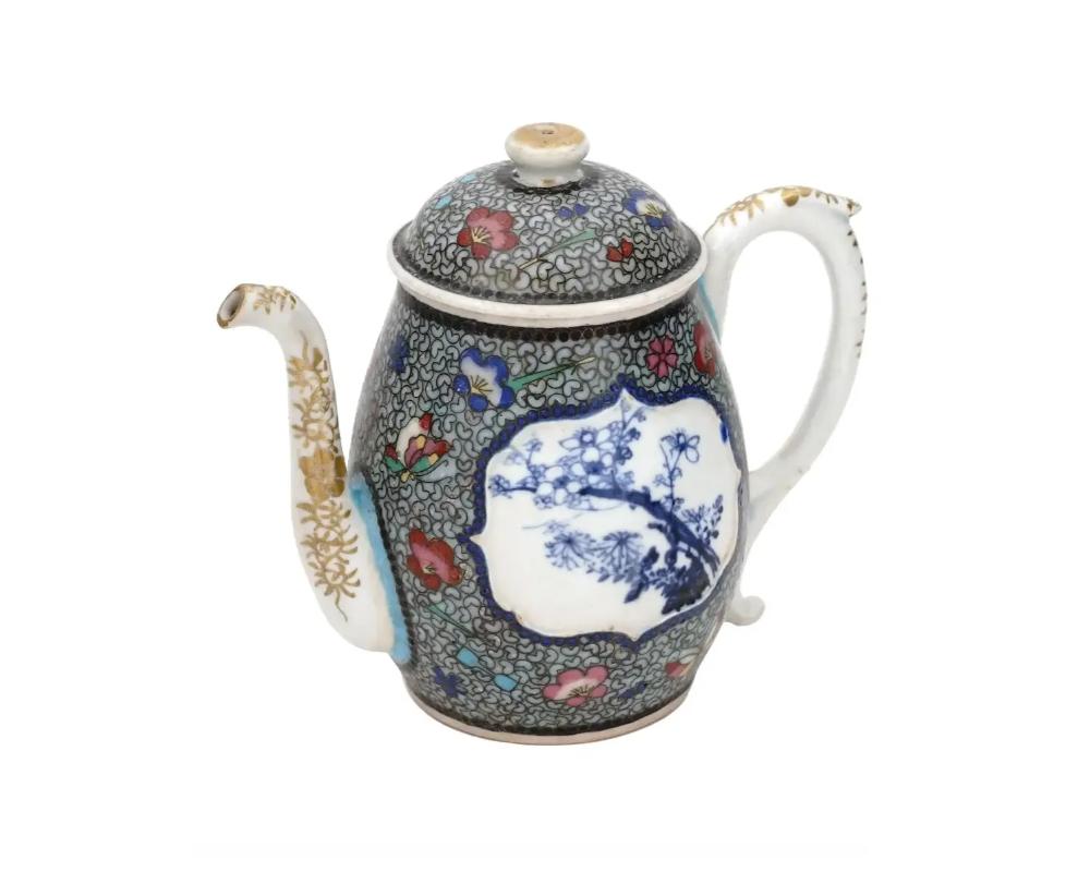 An antique Japanese porcelain teapot. Early Meiji The body and lid are garnished with thin wire cloisonne decor, flowers and butterflies. Hand-painted cobalt blue medallions of blooming sakura and bamboo trees embellish the sides. The white spout